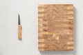 A knife and an oak spliced Ã¢â¬â¹Ã¢â¬â¹wooden cutting board are on burlap. The cross-section of the oak plank has a mosaic texture. Back